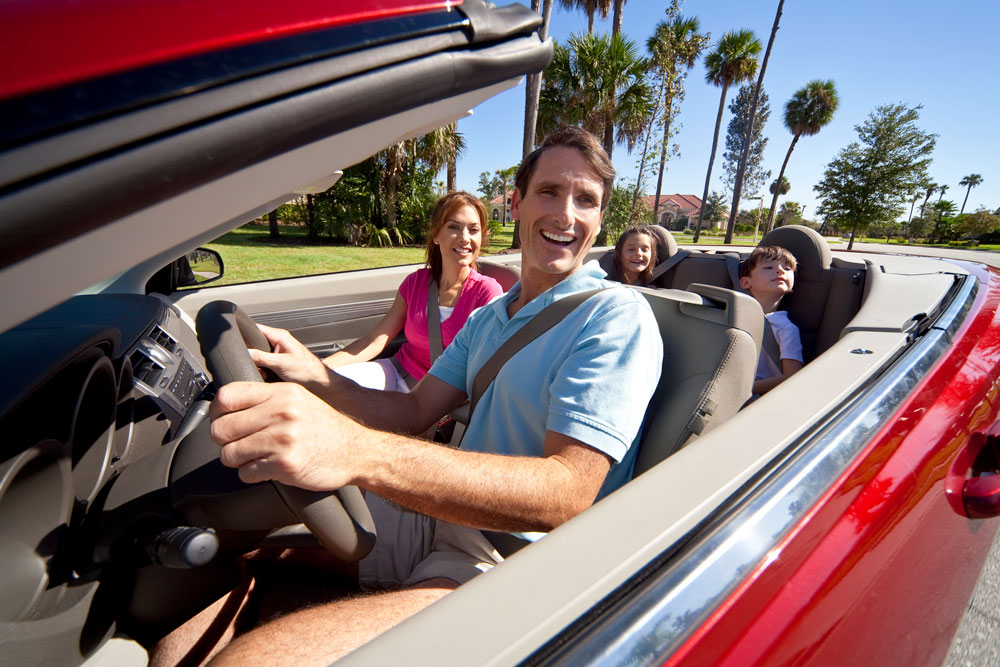 Smiling family driving convertible car in St. Petersburg, Florida